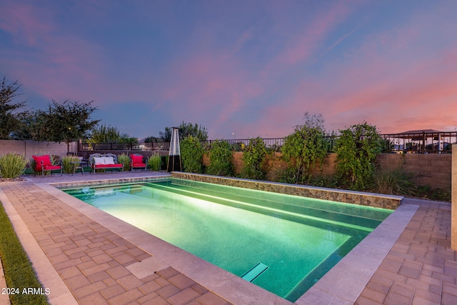 pool at dusk with a patio area