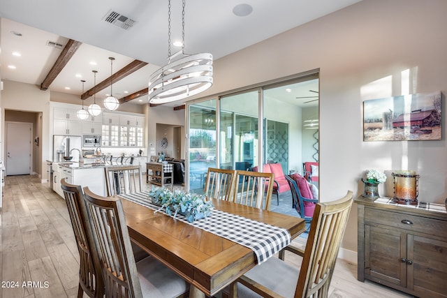 dining room with an inviting chandelier, light wood-type flooring, and beamed ceiling