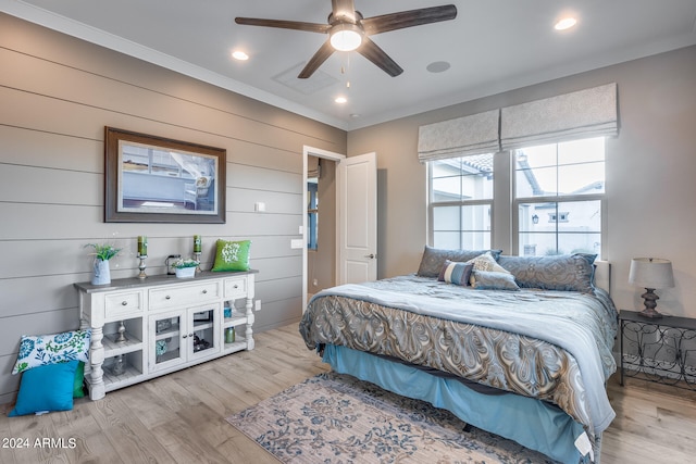 bedroom with ornamental molding, light wood-type flooring, ceiling fan, and wooden walls