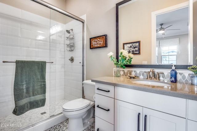 bathroom featuring a shower with shower door, backsplash, vanity, ceiling fan, and toilet