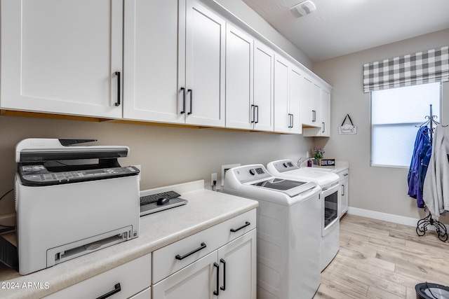 washroom featuring light hardwood / wood-style flooring, cabinets, and washing machine and dryer