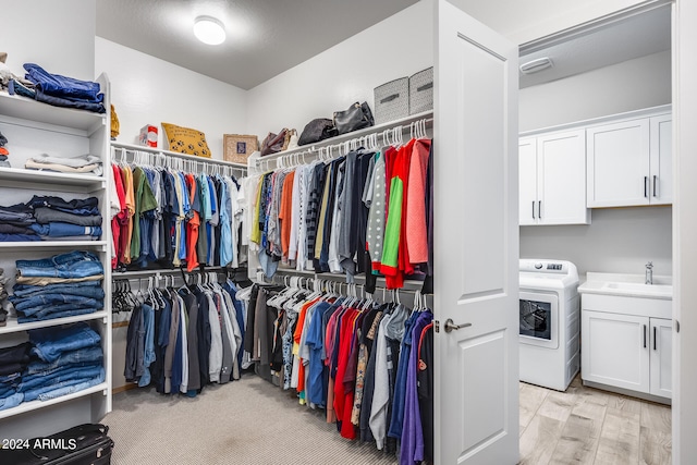 walk in closet featuring light wood-type flooring, sink, and washer / dryer