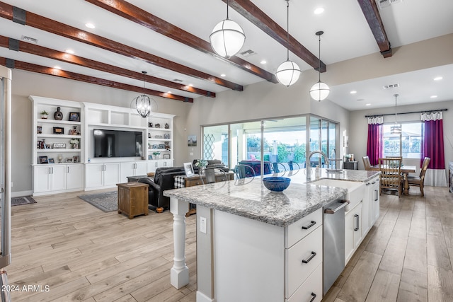 kitchen featuring light stone counters, white cabinets, light wood-type flooring, decorative light fixtures, and a kitchen island with sink