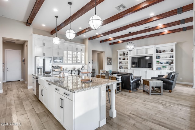 kitchen with light hardwood / wood-style floors, an island with sink, white cabinets, hanging light fixtures, and stainless steel appliances