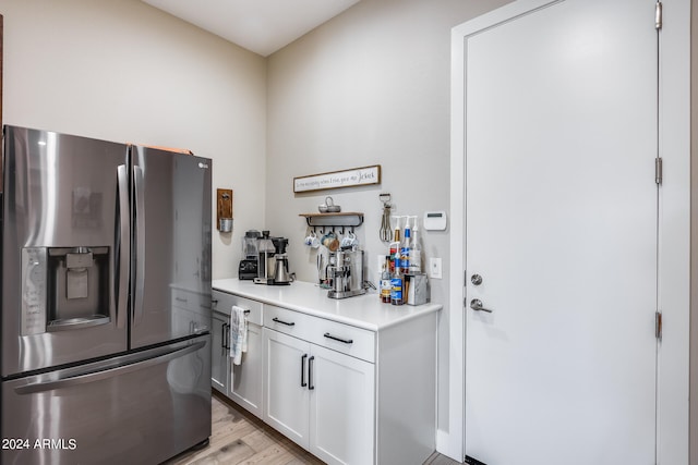 kitchen with light hardwood / wood-style flooring, white cabinets, and stainless steel fridge