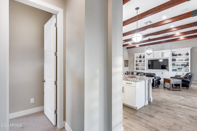 kitchen featuring light stone counters, white cabinets, beam ceiling, hanging light fixtures, and light hardwood / wood-style flooring