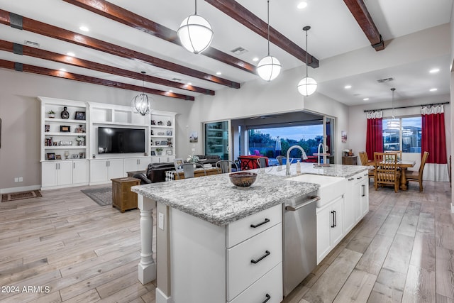 kitchen featuring white cabinetry, light stone counters, light hardwood / wood-style flooring, decorative light fixtures, and a center island with sink