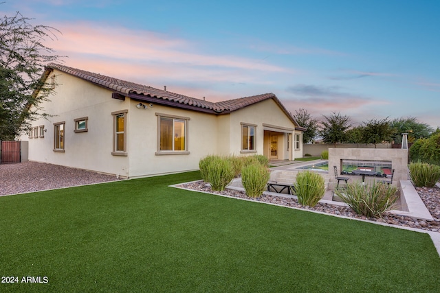 back house at dusk with a lawn and a patio area