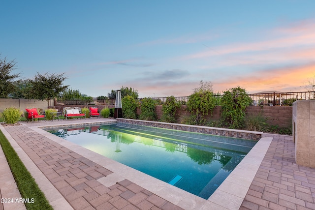 pool at dusk with a patio area