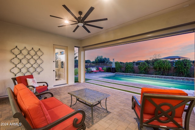 patio terrace at dusk featuring ceiling fan and a fenced in pool