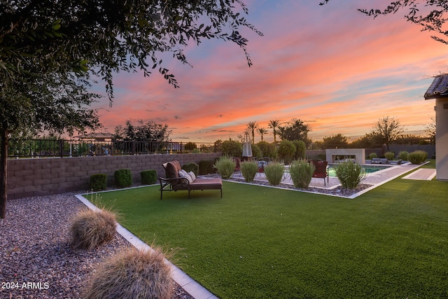 yard at dusk with a fenced in pool and a fire pit