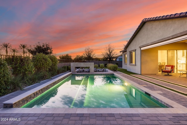 pool at dusk with a patio area