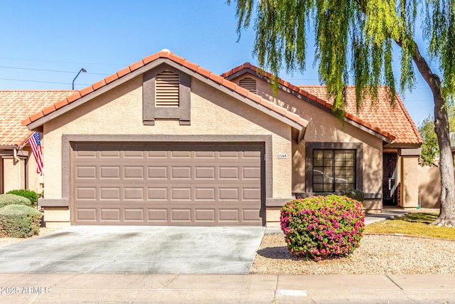 view of front of home with a garage, concrete driveway, a tile roof, and stucco siding