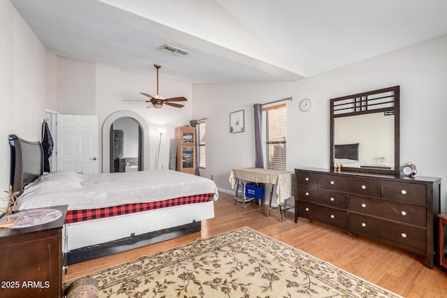 bedroom featuring arched walkways, visible vents, a ceiling fan, vaulted ceiling, and wood finished floors