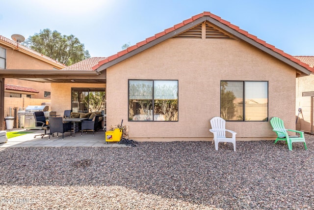 back of house with stucco siding, a tiled roof, fence, and a patio