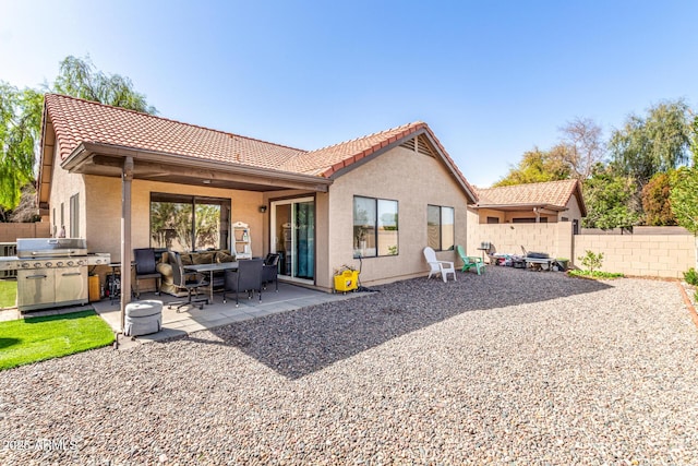 rear view of property featuring stucco siding, fence, and a patio