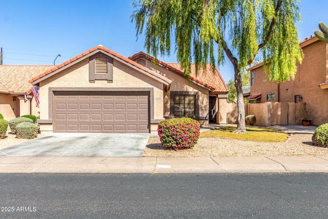 view of front of house featuring a tile roof, stucco siding, an attached garage, fence, and driveway