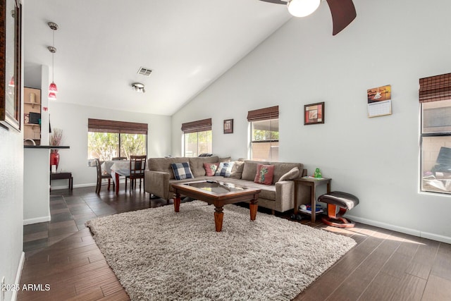 living area with baseboards, visible vents, ceiling fan, dark wood-type flooring, and high vaulted ceiling