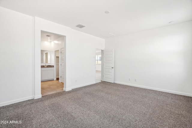 unfurnished bedroom with light colored carpet and connected bathroom