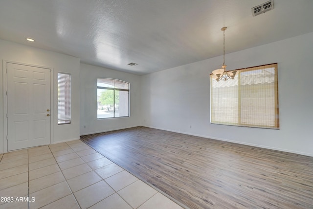 tiled foyer entrance featuring an inviting chandelier