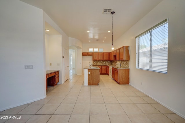 kitchen with electric stove, light tile floors, a center island with sink, backsplash, and hanging light fixtures