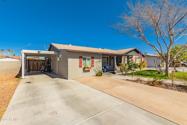 single story home featuring a carport, driveway, fence, and stucco siding