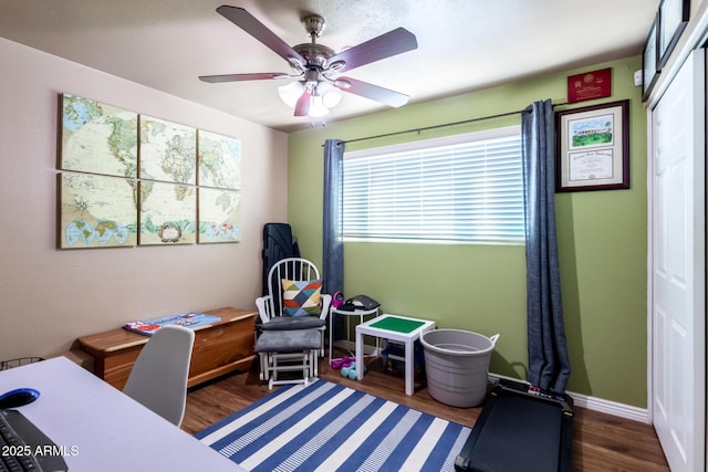 interior space with a ceiling fan, baseboards, and wood finished floors