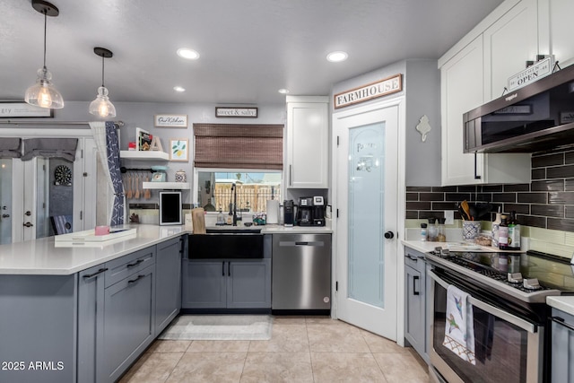 kitchen with decorative backsplash, stainless steel appliances, light countertops, white cabinetry, and a sink