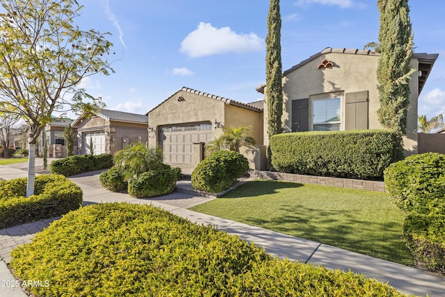 mediterranean / spanish house with a front yard, a tiled roof, an attached garage, and stucco siding