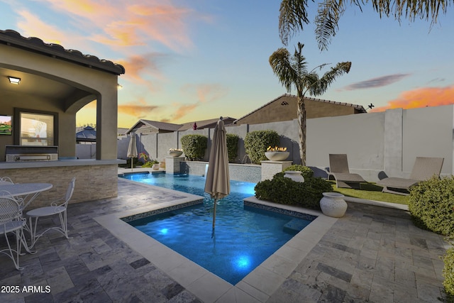 view of swimming pool featuring a patio, exterior kitchen, a fenced backyard, and a fenced in pool