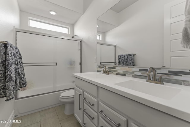 full bathroom with double vanity, toilet, enclosed tub / shower combo, and a sink