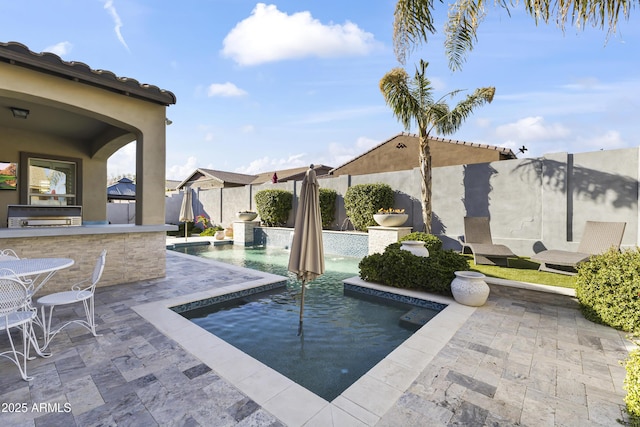 view of swimming pool featuring a fenced backyard, a fenced in pool, an outdoor kitchen, and a patio area