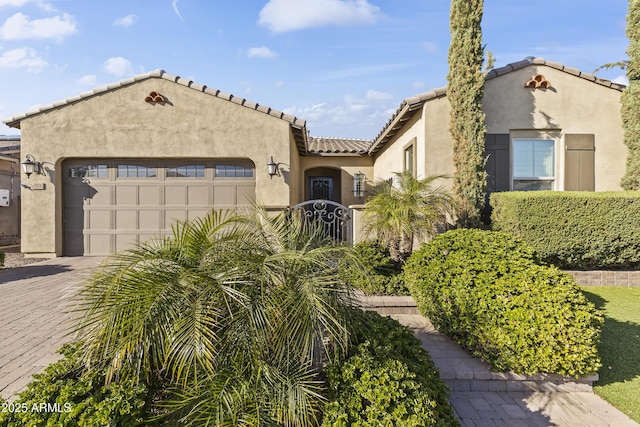 mediterranean / spanish-style home with stucco siding, a garage, driveway, and a tile roof