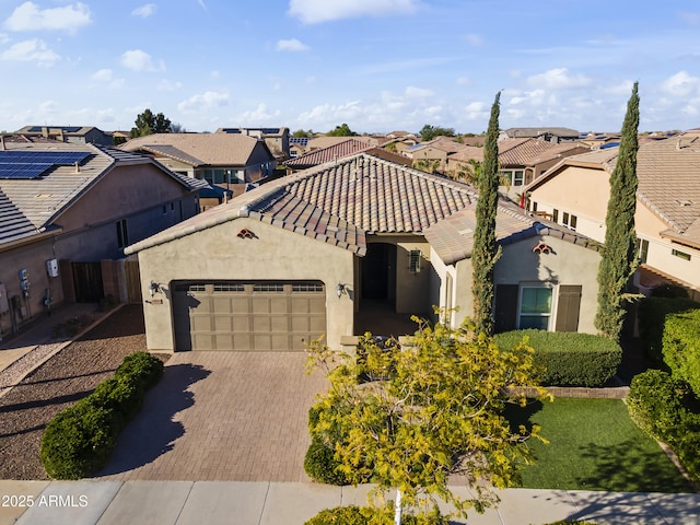 view of front of house featuring decorative driveway, a garage, a residential view, and a tiled roof