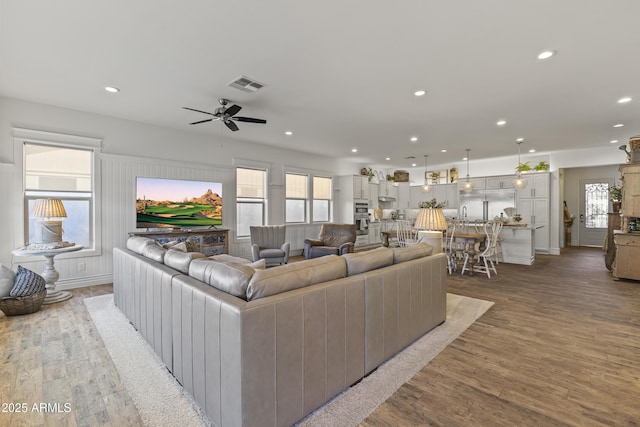 living room with a wealth of natural light, visible vents, and light wood finished floors