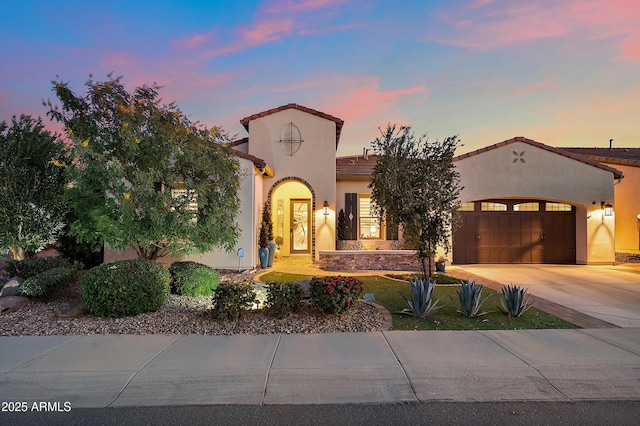 mediterranean / spanish-style home featuring stucco siding, a garage, driveway, and a tiled roof