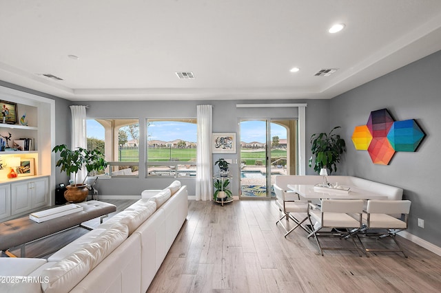 living room with a wealth of natural light, visible vents, and light wood finished floors