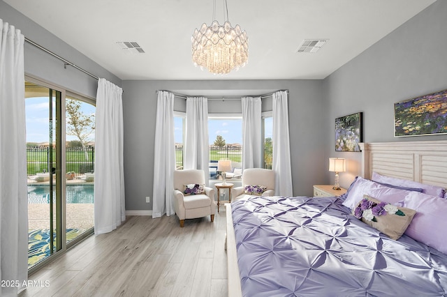 bedroom featuring a notable chandelier, light hardwood / wood-style floors, access to outside, and multiple windows