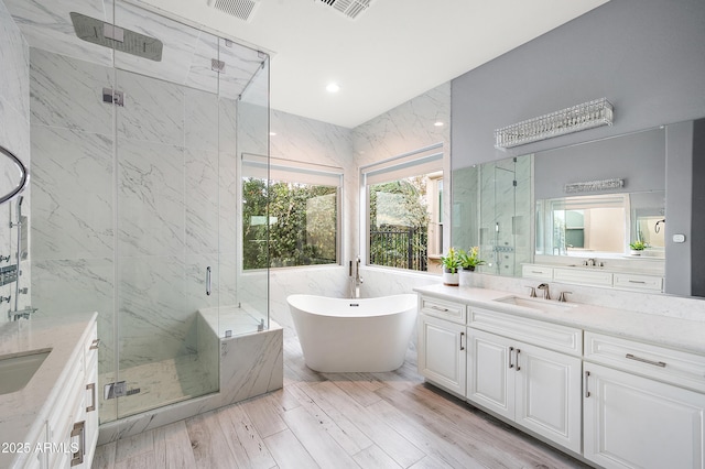 bathroom with a marble finish shower, tile walls, recessed lighting, a soaking tub, and vanity