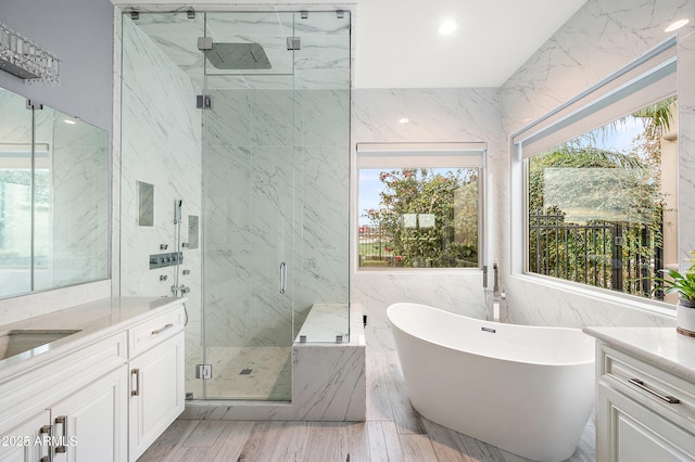 full bathroom with recessed lighting, a marble finish shower, tile walls, a freestanding bath, and vanity