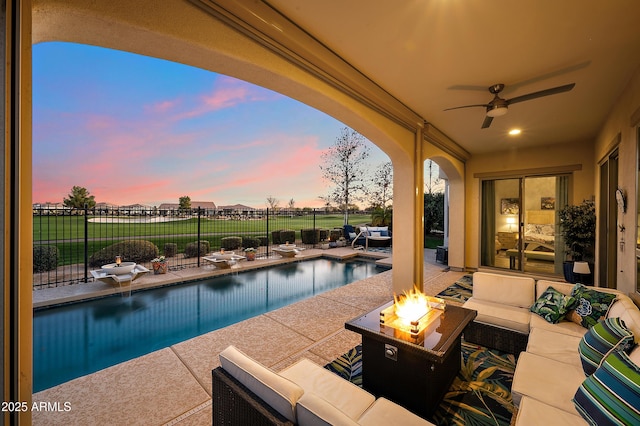 pool at dusk featuring an outdoor living space with a fire pit, a patio, a fenced backyard, and a fenced in pool