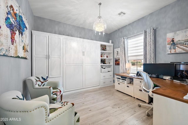 home office with light hardwood / wood-style flooring and a chandelier