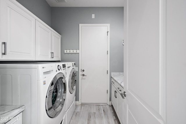 laundry area with washer and dryer, cabinets, and light hardwood / wood-style flooring