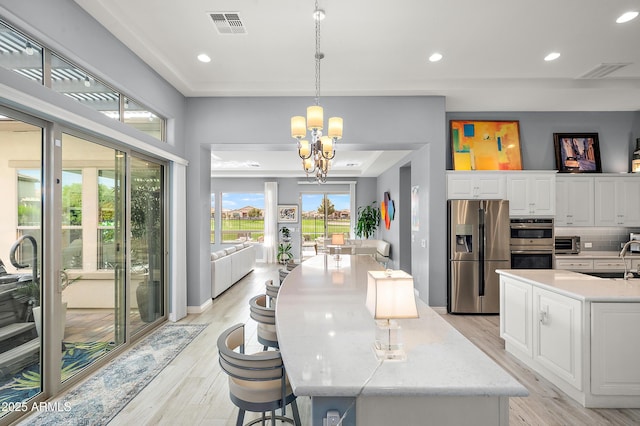 kitchen featuring hanging light fixtures, stainless steel appliances, backsplash, a chandelier, and white cabinets