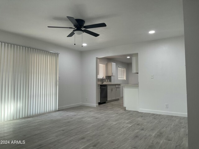 unfurnished living room with light hardwood / wood-style flooring, ceiling fan, and sink