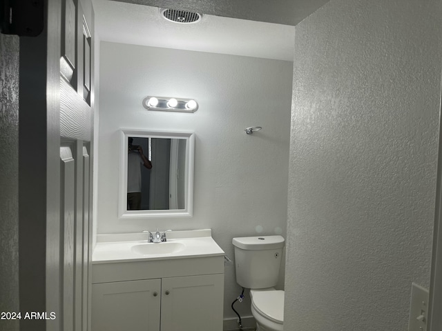 bathroom with vanity, a textured ceiling, and toilet