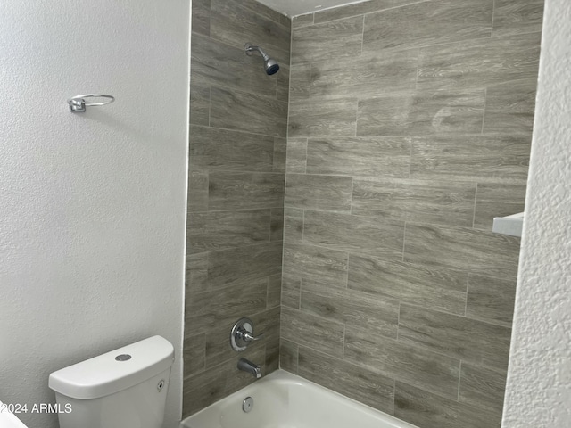 bathroom featuring toilet and tiled shower / bath