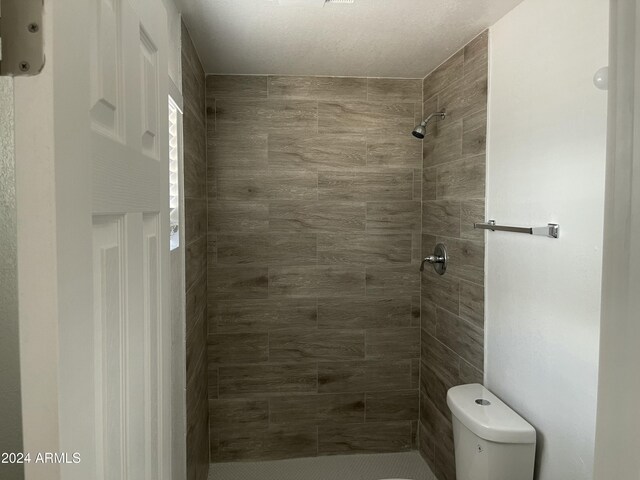 bathroom with tiled shower and toilet