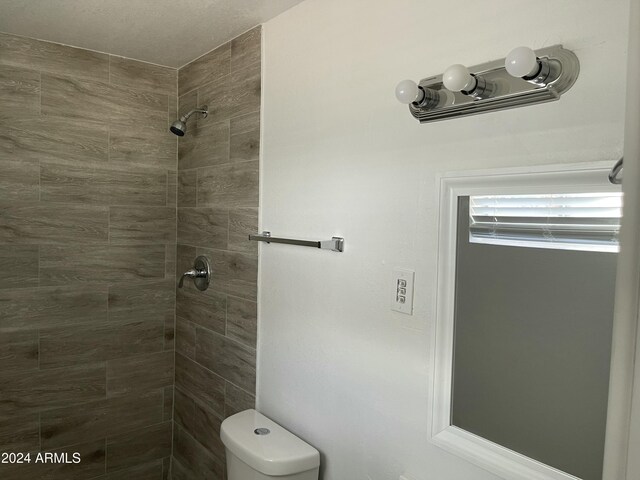 bathroom featuring a tile shower and toilet