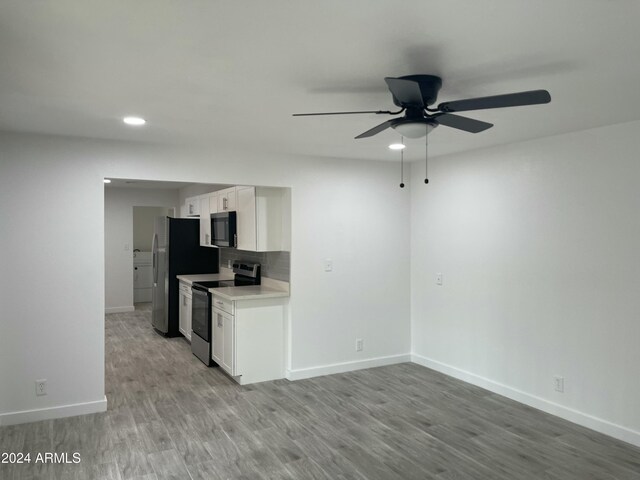 kitchen featuring backsplash, white cabinetry, light wood-type flooring, and appliances with stainless steel finishes